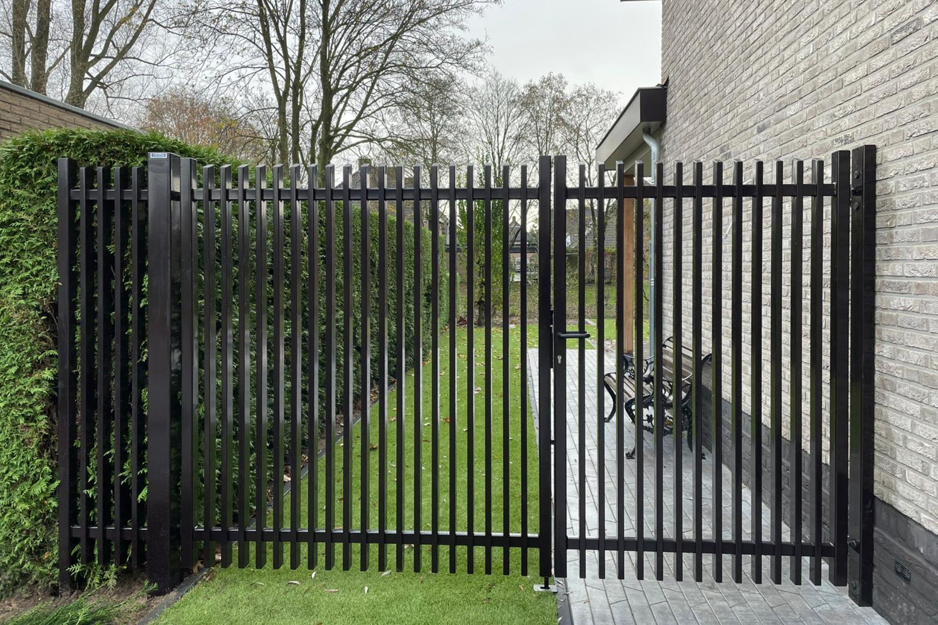 Zijkant van een woning, met toegang via een stalen looppoort.