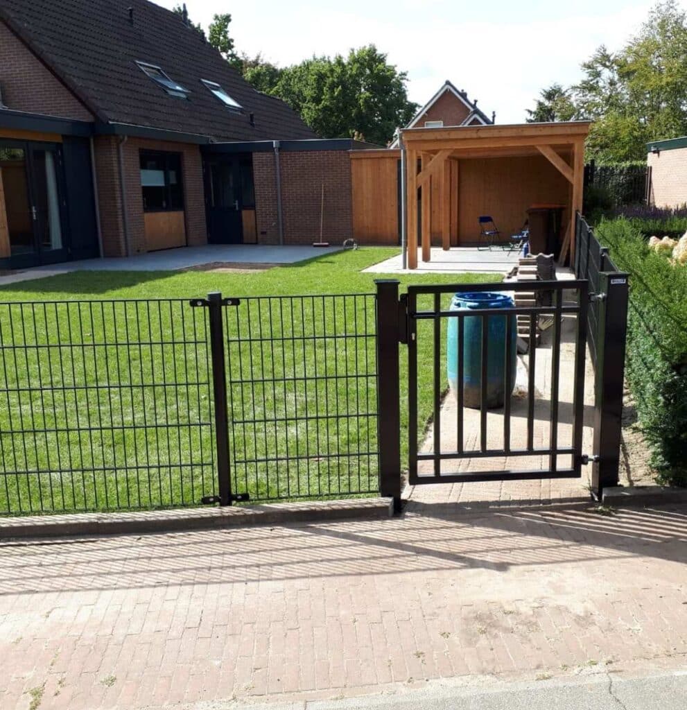 Impressie van een laag dubbelstaafmat hekwerk met looppoort, als omheining van een tuin. Het hekwerk heeft een moderne stijl.